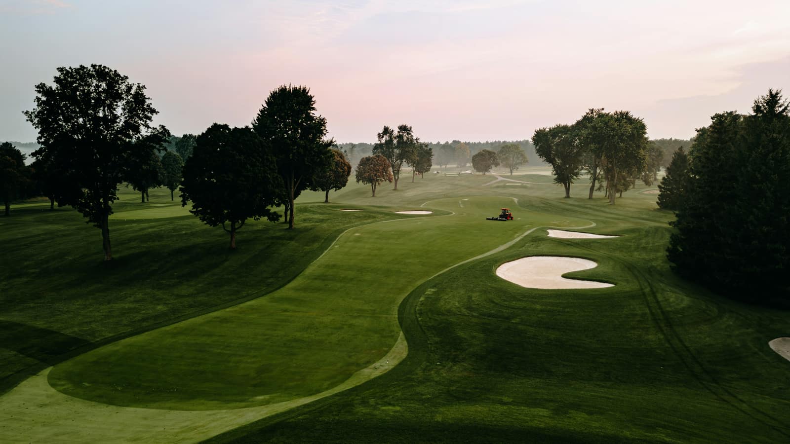 Early morning mist over a green fairway with trees